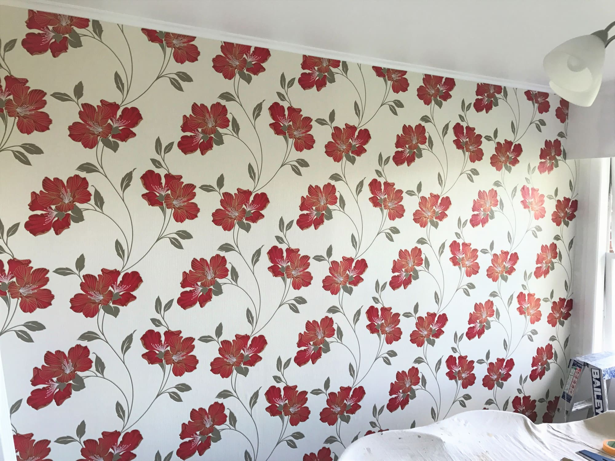 Red floral wallpaper across a bedroom feature wall.