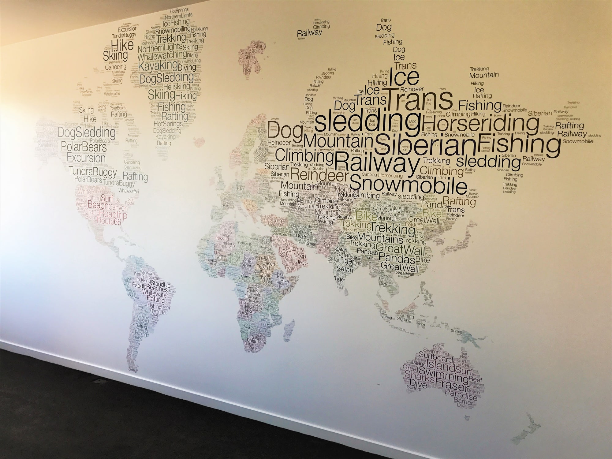 A world map mural made entirely from words, covering a whole wall.